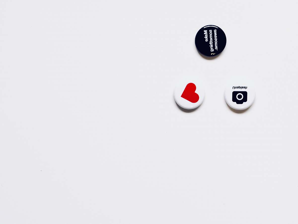 australia three white and black button pins on white surface red